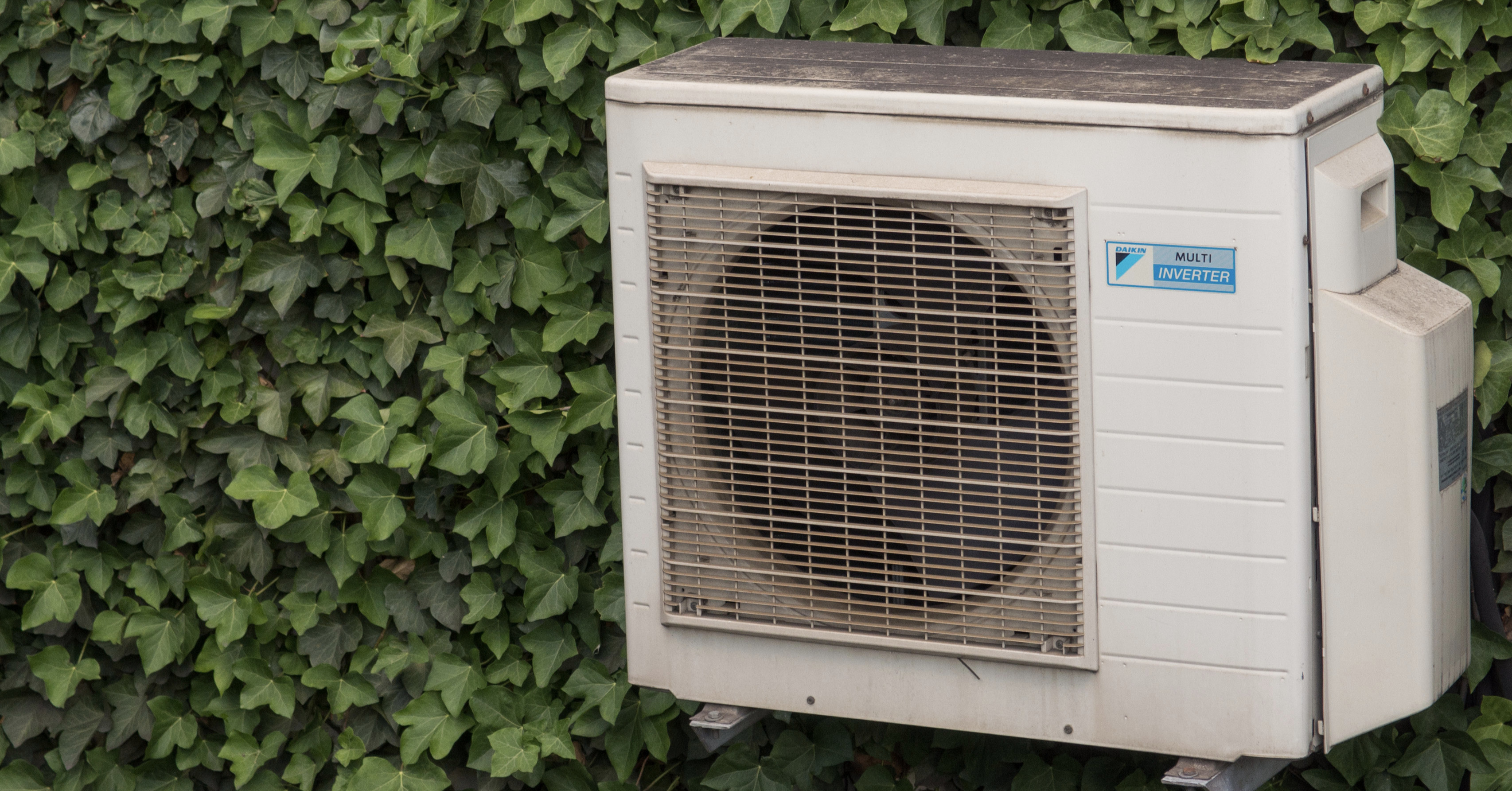 Air conditioner compressor on the ivy wall