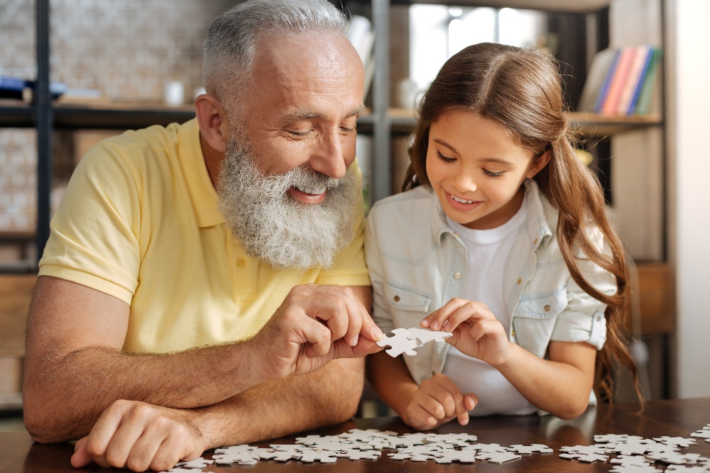 Grandfather and granddaughter connecting two jigsaw puzzle pieces-1