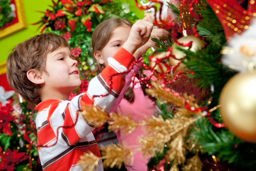 Happy kids decorating a Christmas tree with ornaments