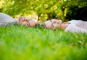 Young loving couple lying at the park  with heads together
